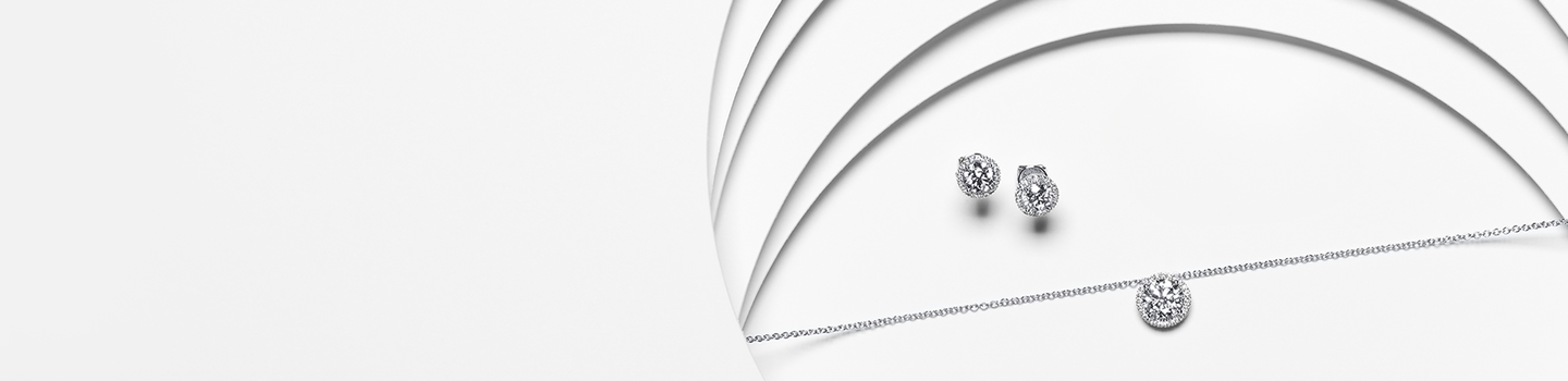 A pair of Birks Snowflake diamond earrings and necklace on a white background.